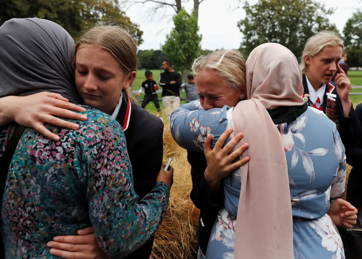 Alunos de uma escola cristã abraçam muçulmanos à espera de notícias de familiares após o tiroteio em Christchurch, na Nova Zelândia.