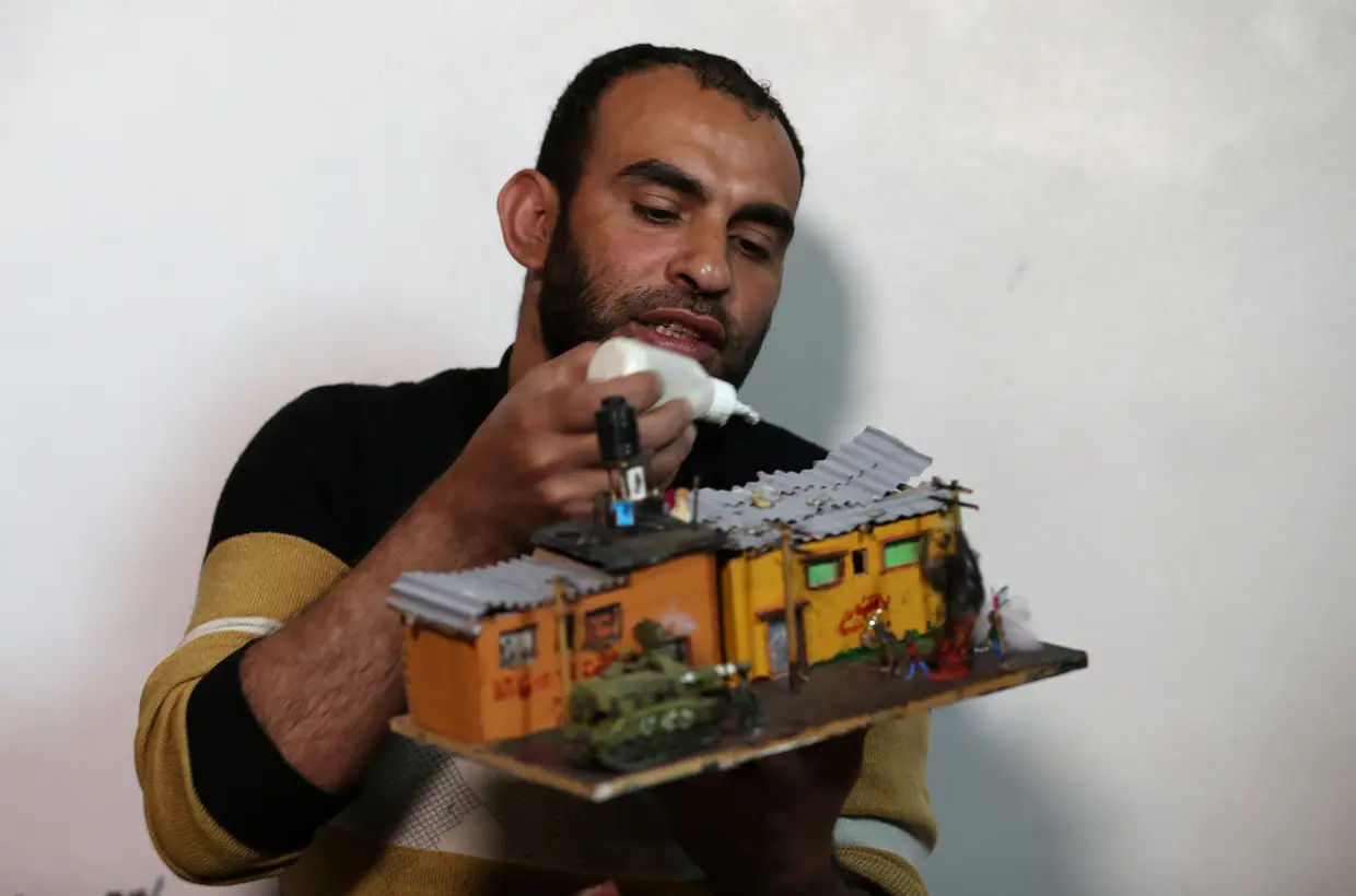 O artista palestiniano Majdi Abu Taqeya trabalha numa casa de miniatura, construída a partir dos destroços deixados para trás nas cenas dos protestos ao longo da fronteira entre Gaza e Israel.