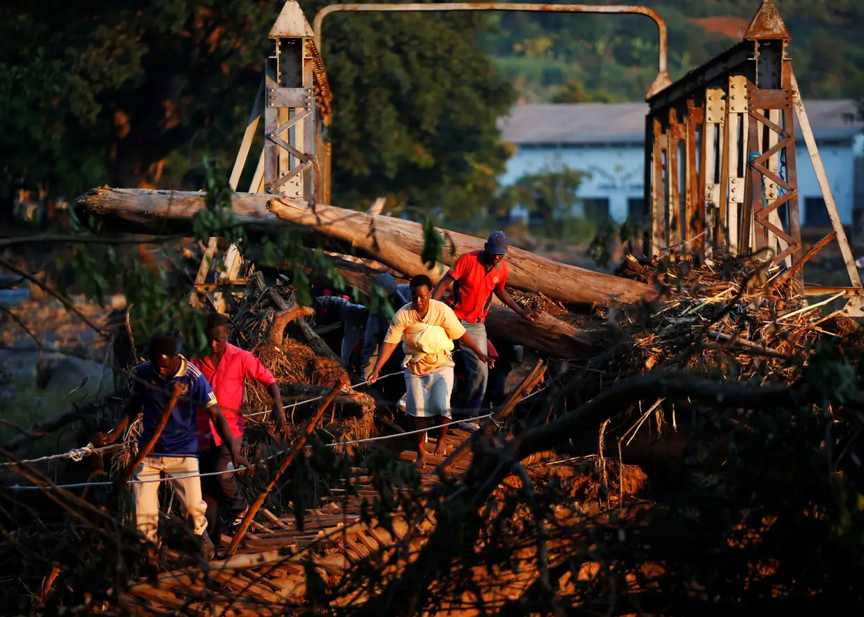 Sobreviventes do ciclone Idai atravessam uma ponte temporária para receber ajuda em Chipinge, no Zimbabué.