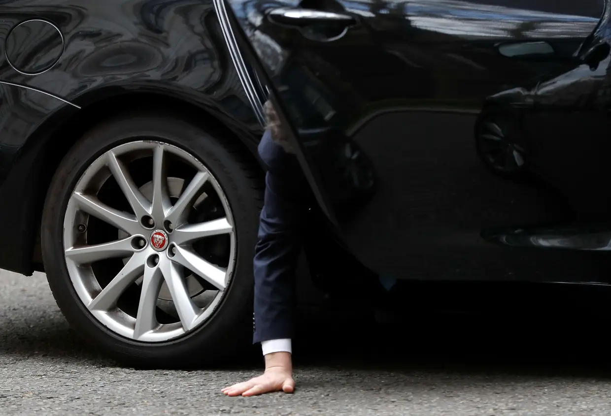 O chefe do Partido Conservador britânico, Julian Smith, tenta apanhar o telemóvel que deixou cair enquanto está sentado dentro do carro, em frente a Downing Street, em Londres.