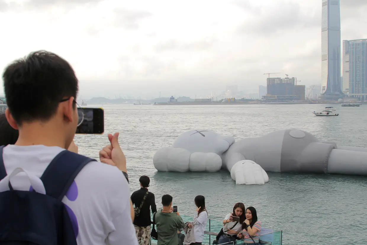 Em Hong Kong, visitantes tiram fotografias perto da escultura insuflável "Companion", do artista norte-americano Brian Donnelly.