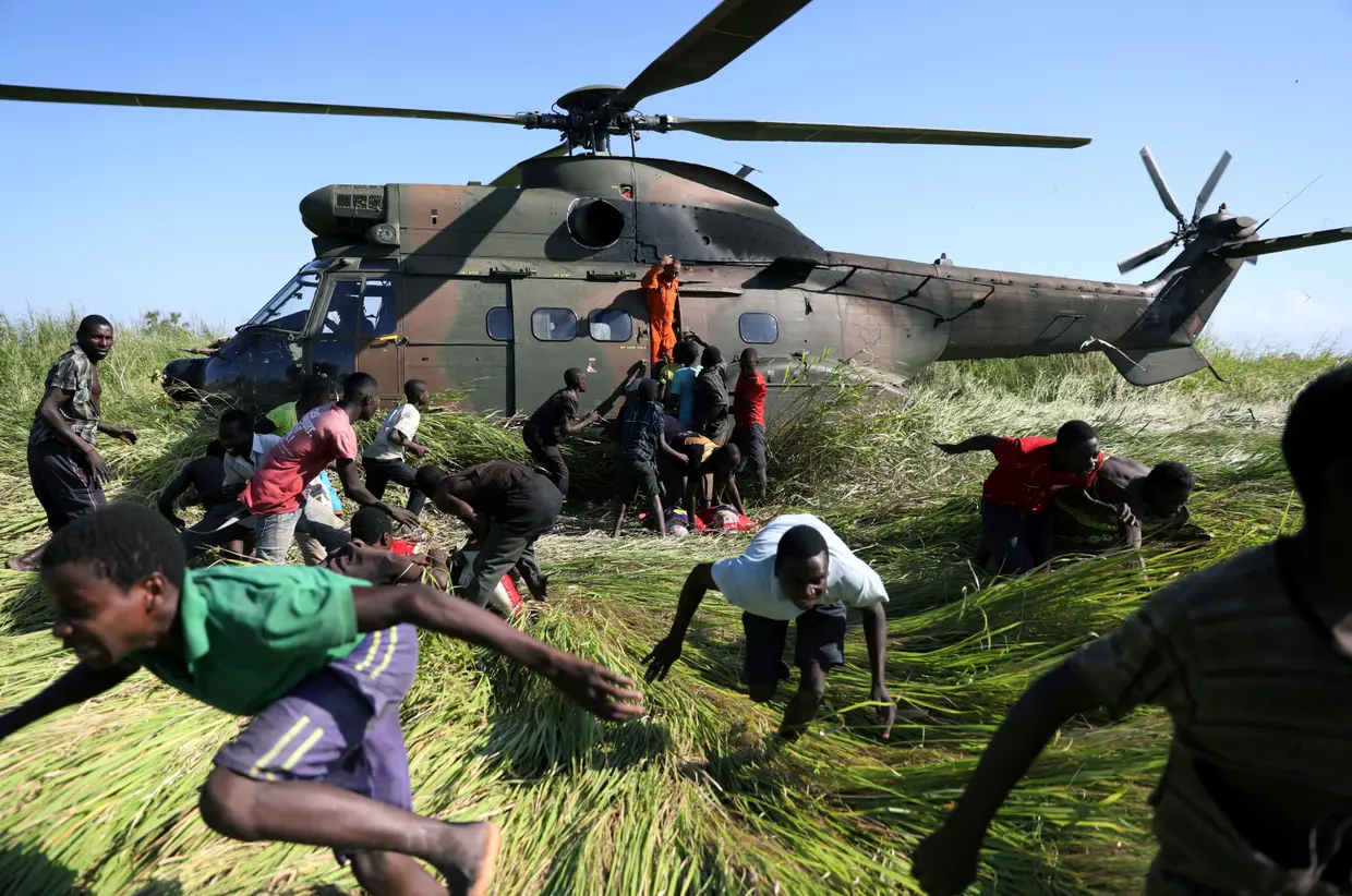 Moçambicanos recolhem ajuda humanitária de um helicóptero da Força Nacional de Defesa da África do Sul.
