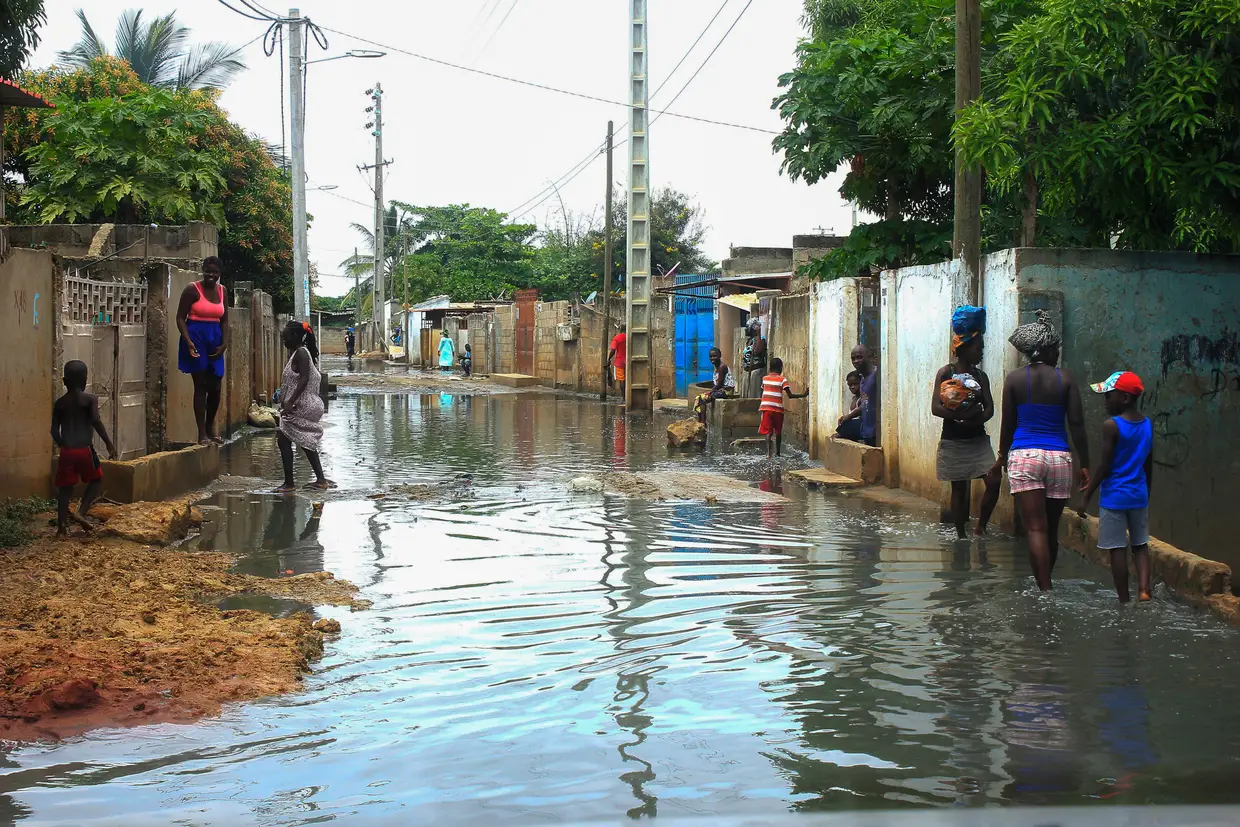 Populares caminham numa rua do Bairro da Boa Esperança após a queda de chuvas fortes em Luanda, Angola.
