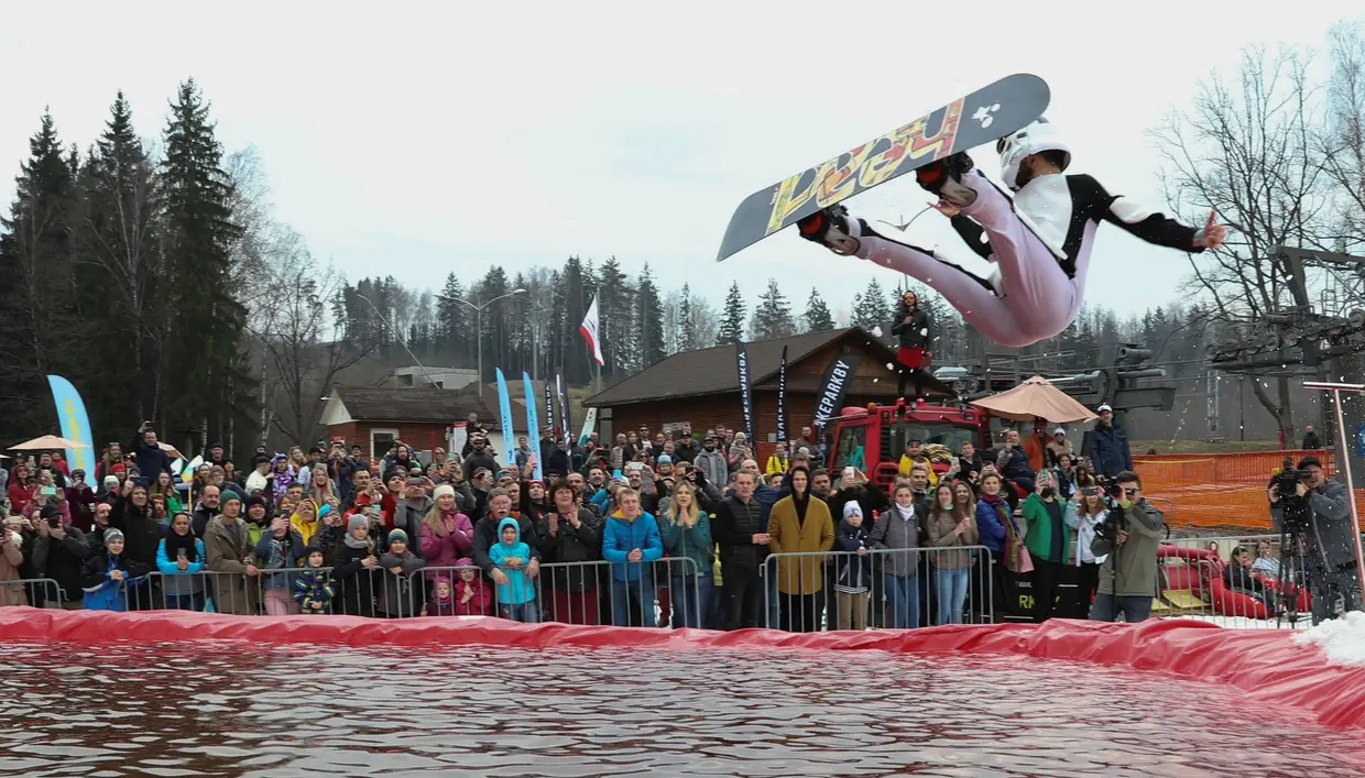 Um snowboarder salta para a água gelada para marcar o fim do inverno, durante a competição "Californication 9.0", em Logoisk, na Bielorrússia.