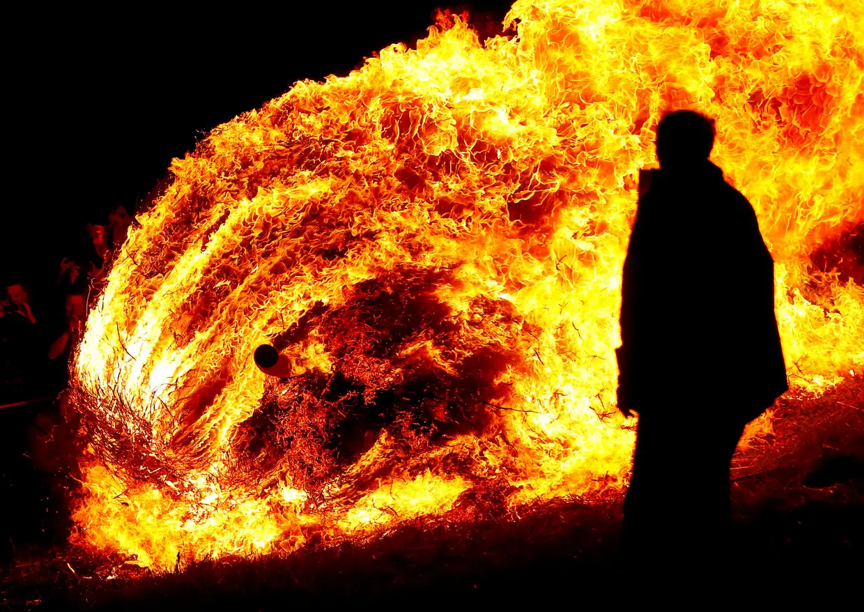 Uma roda de madeira recheada com palha e incendiada desce por uma colina durante a celebração do tradicional 'Osterraederlauf' em Luegde, Alemanha.