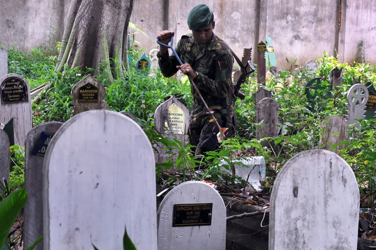 Um oficial da força-especial da polícia do Sri Lanka inspeciona um cemitério muçulmano durante uma operação de buscas em Colombo, após os ataques que fizeram centenas de mortos.