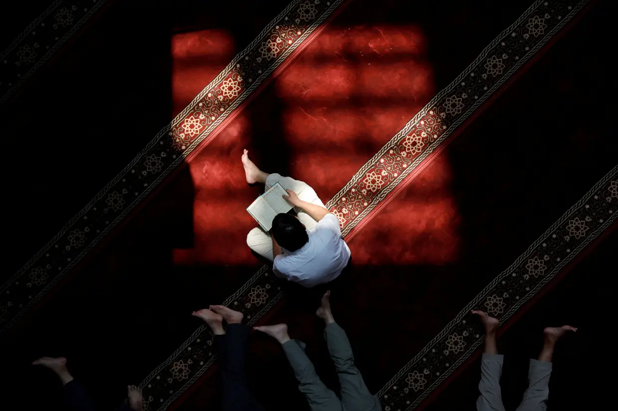 Um muçulmano lê o Alcorão enquanto outros descansam numa mesquita em Jakarta durante o mês do Ramadão, Indonésia.