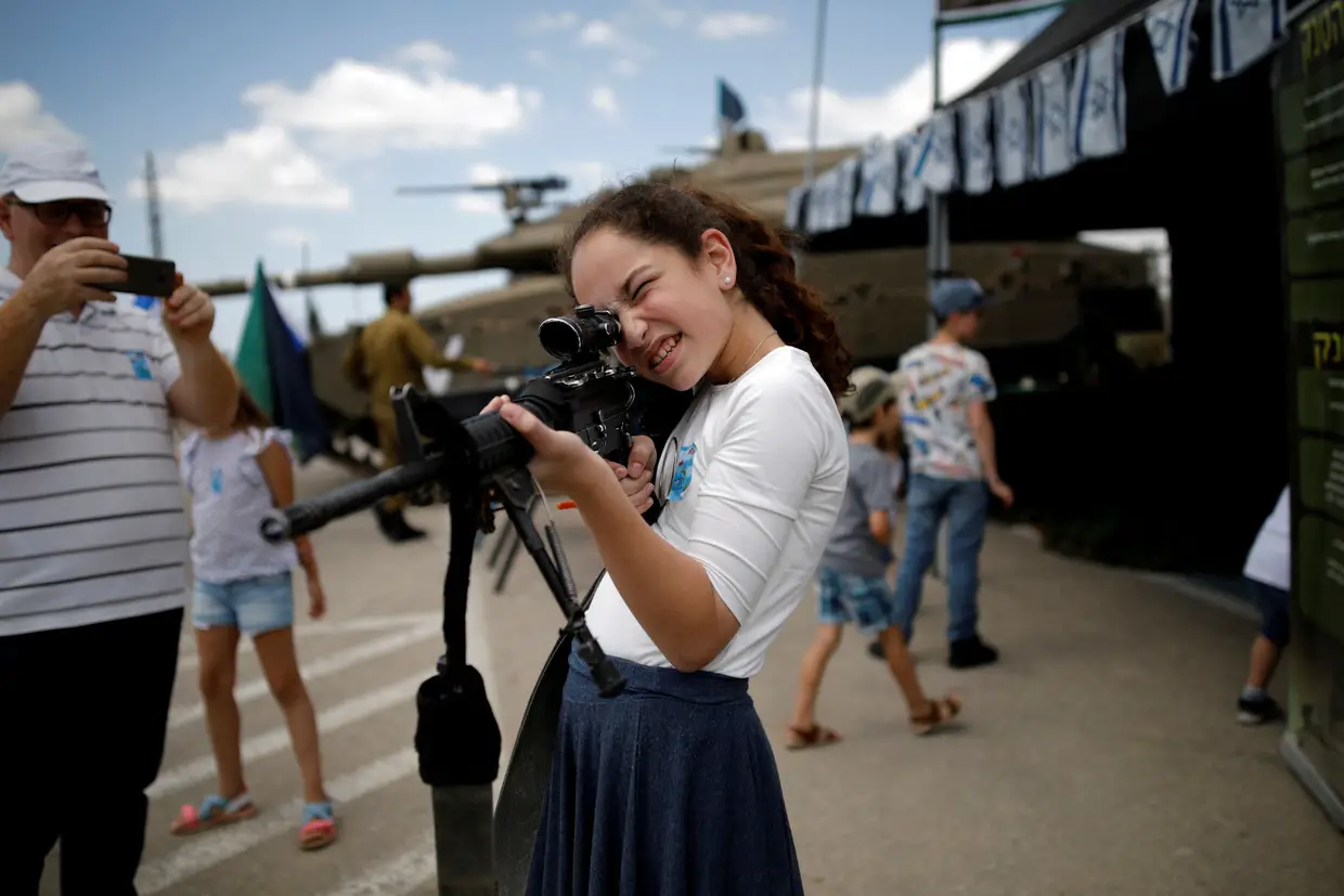 Uma adolescente experimenta um arma automática depois da cerimónia do “Memorial Day” em Latrun, Israel.