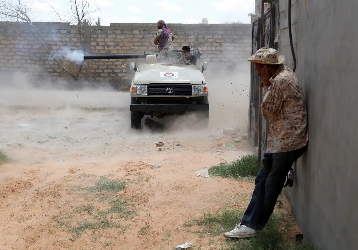 Um combatente leal ao Governo da Líbia abre fogo contra as forças leais ao militar Khalifa Hafter, Trípoli, Líbia.