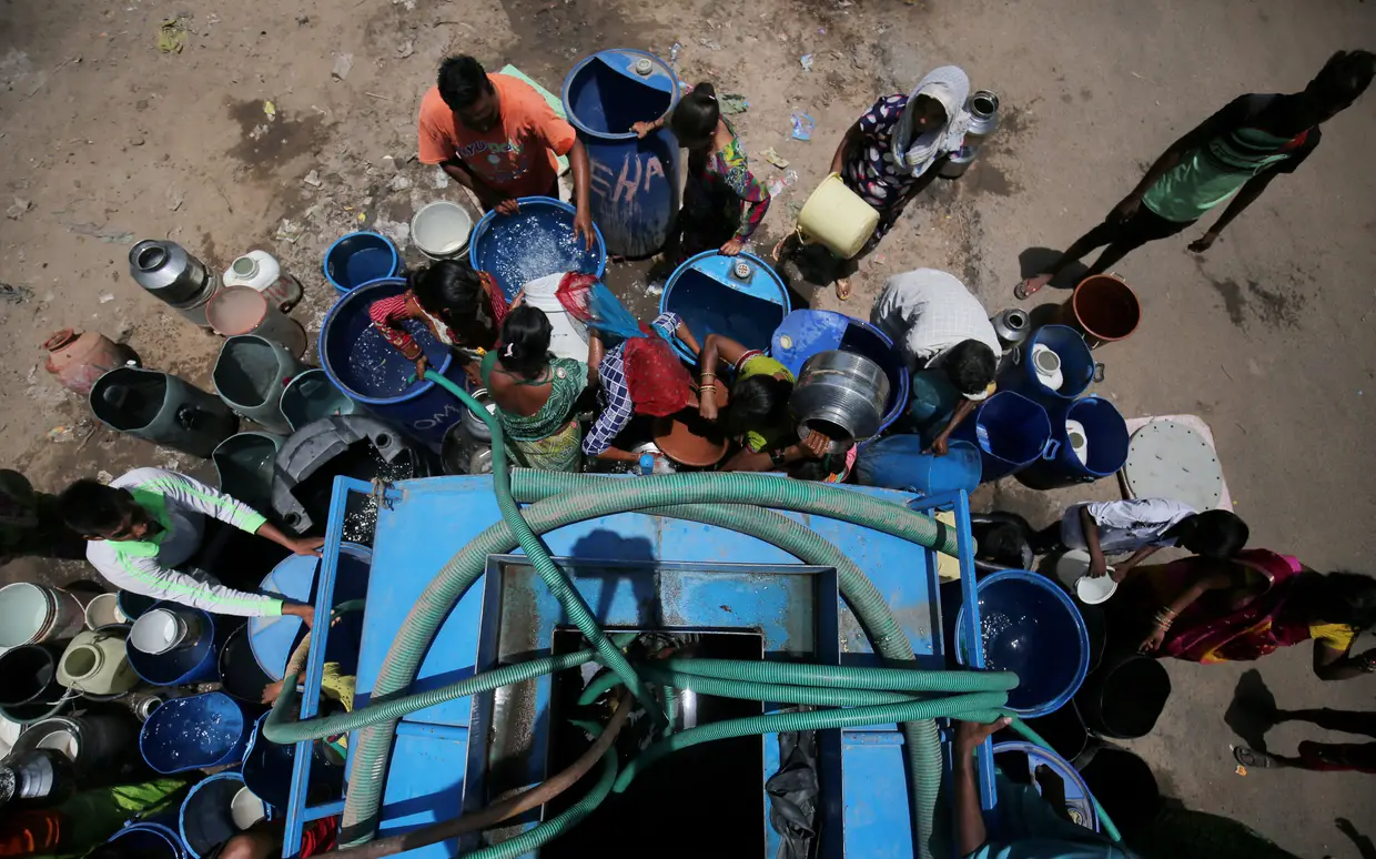 Indianos enchem baldes com água num dia de muito calor, em Ahmedabad.