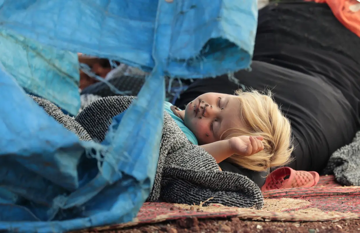 Uma criança síria deslocada dorme no chão na cidade de Atmeh, na província de Idlib.
