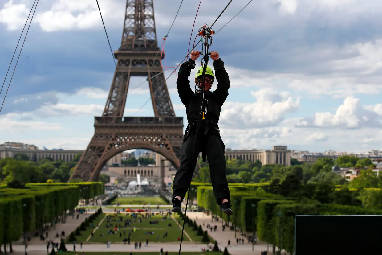 Um homem desce a Torre Eiffel, em Paris, num slide.