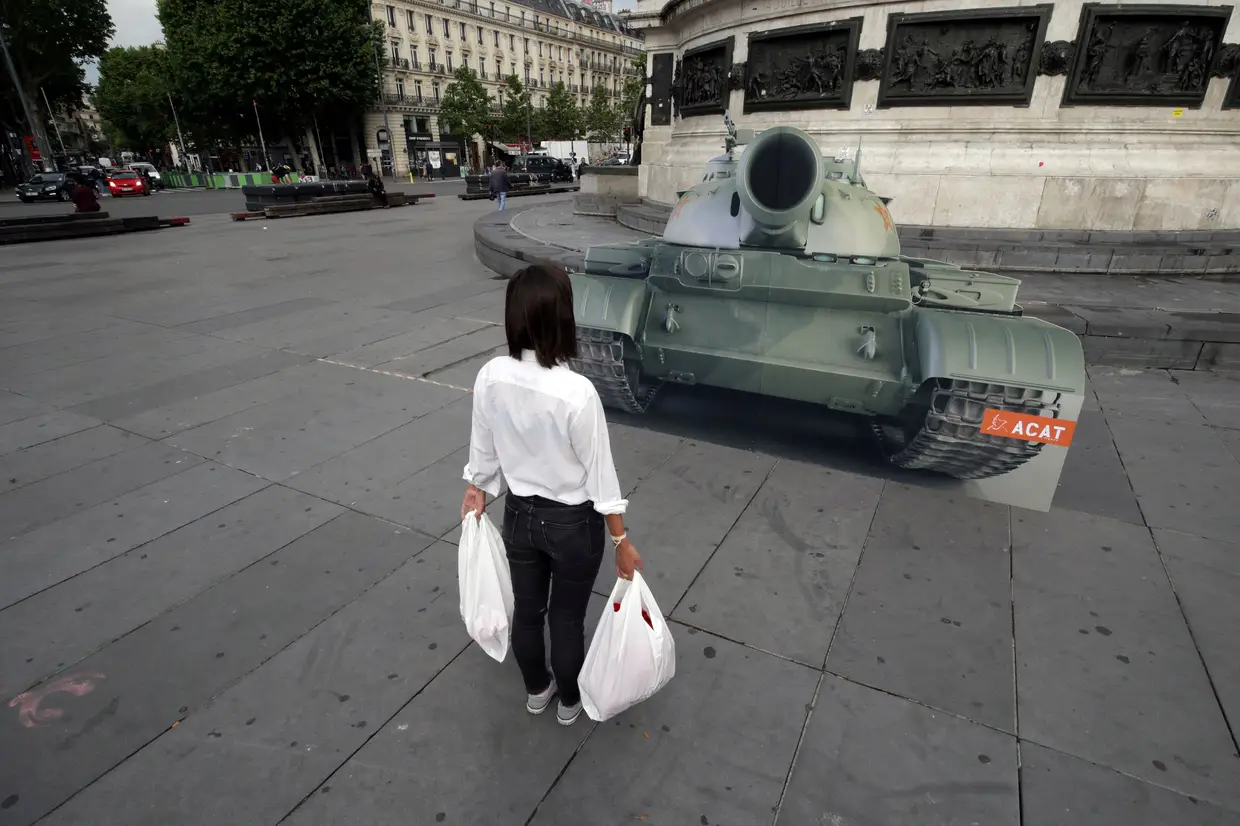 Um membro do Movimento Mundial de Direitos Humanos posa em frente à imagem deum tanque em Paris, França, pelo 30.º aniversário do protesto em Tiananmen.