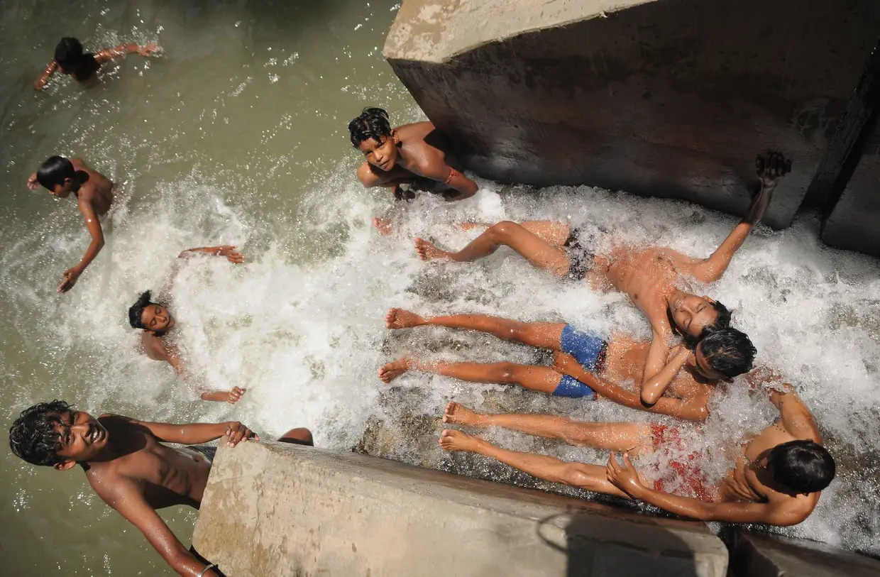 Jovens refrescam-se num canal de Nova Deli, na Índia, onde os termómetros podem atingir os 46 graus.