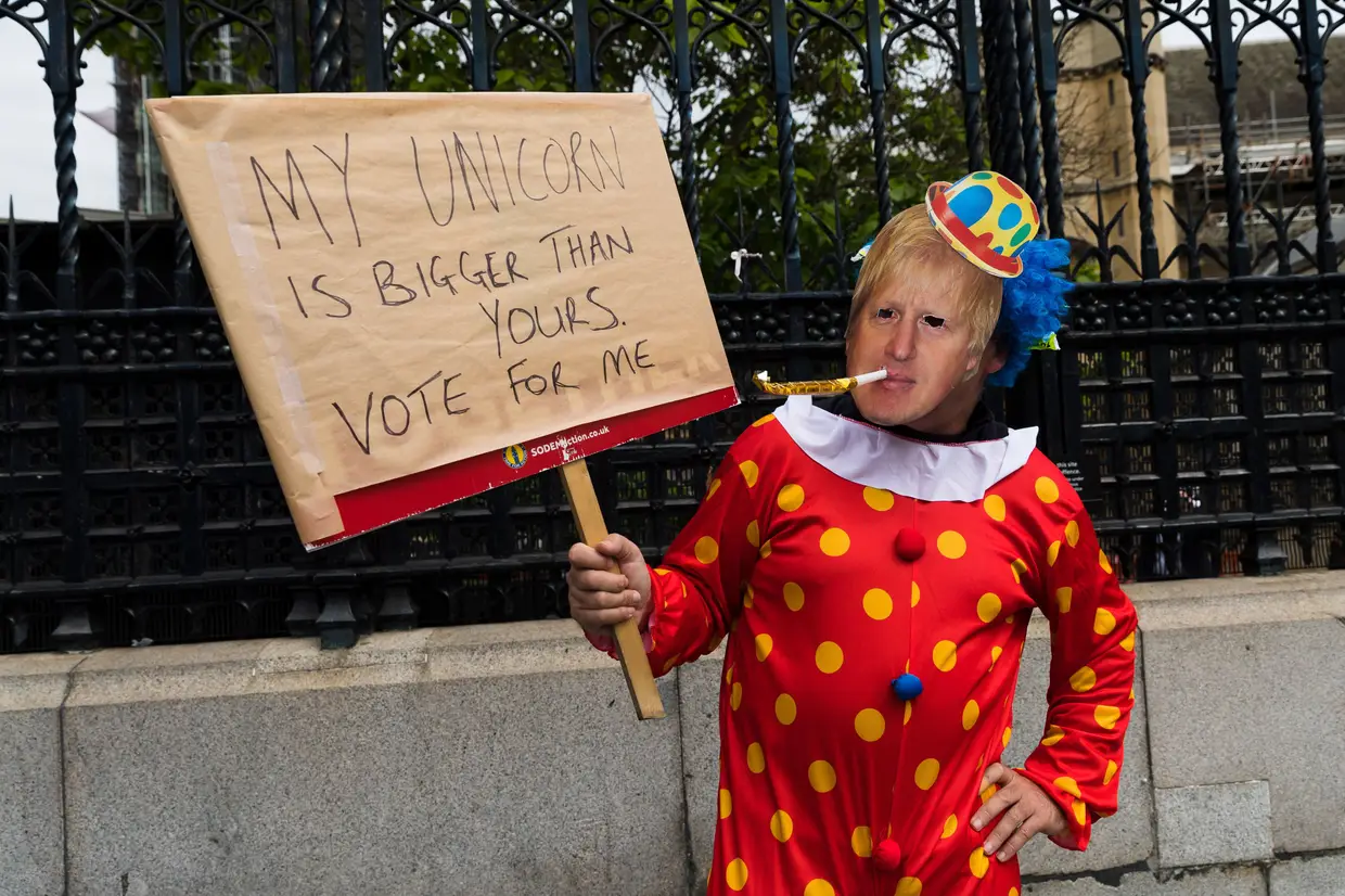 Um manifestante vestido de palhaço com uma máscara de Boris Johnson segura um cartaz onde se lê "O meu unicórnio é maior que o teu. Vota em mim", durante um protesto junto ao Parlamento em Londres, Reino Unido.