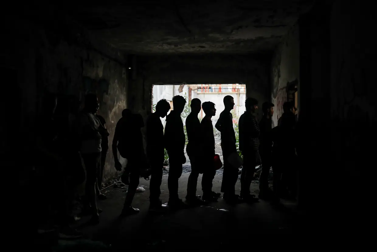 Migrantes fazem fila para receber comida junto à fronteira entre a Sérvia e a Croácia.