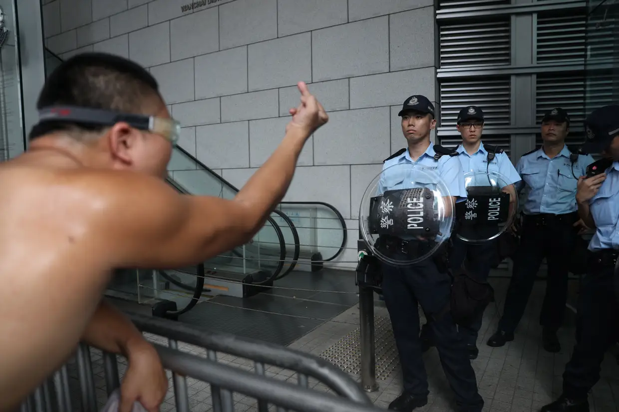 Um manifestante gesticula para um polícia, junto à sede da polícia de Wanchai, em Hong Kong.