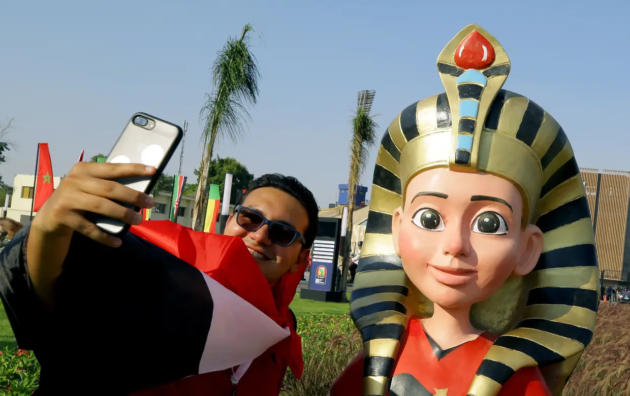 Um adepto posa com a mascote Tut, antes do jogo de abertura da Liga das Nações de África, entre o Egito e o Zimbabué, no Estádio Internacional de Cairo, na capital egípcia.