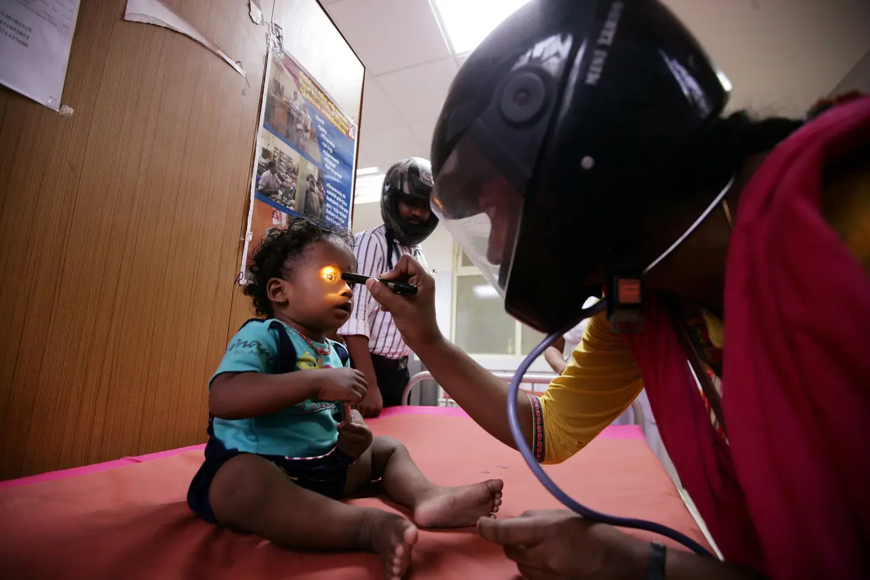 Um médico com um capacete examina um paciente dentro de uma enfermaria durante uma greve de médicos em Chennai, Índia, após uma onde de assaltos por familiares de pacientes.