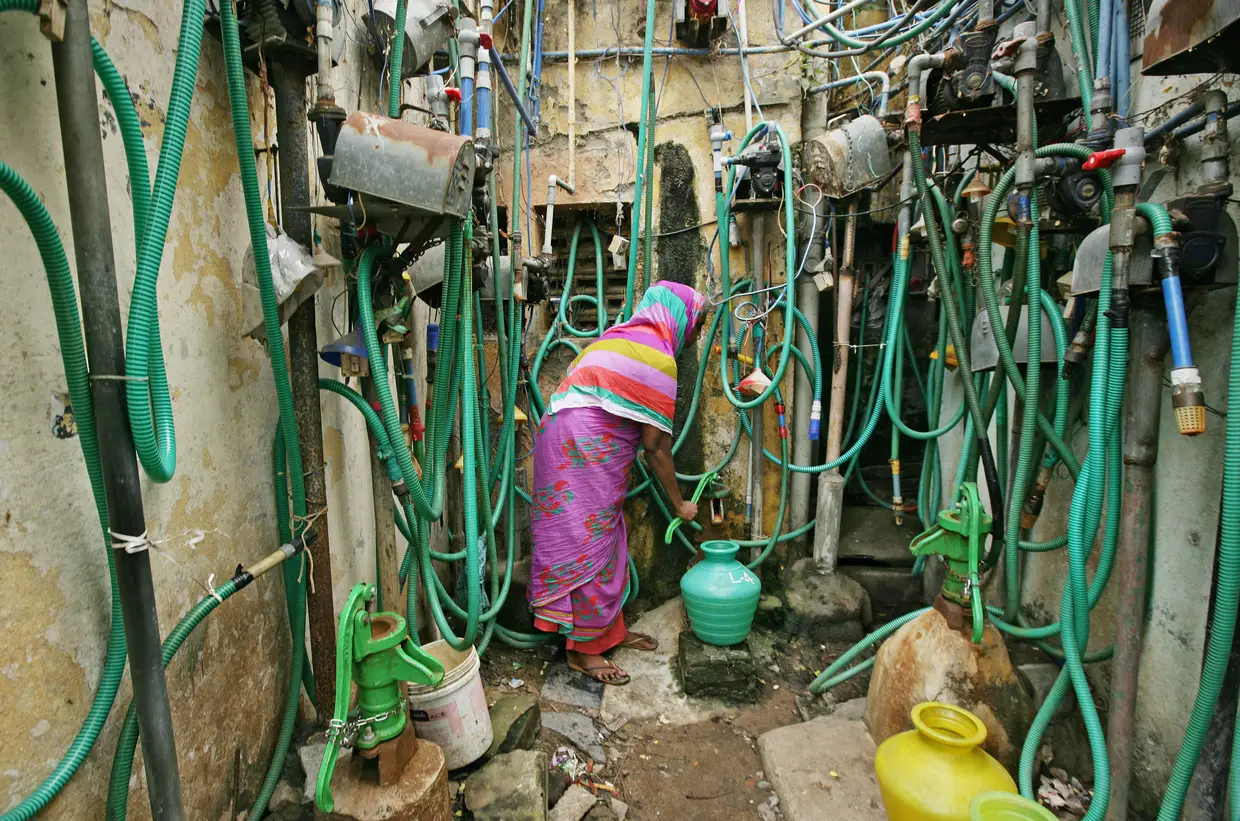 Mulher usa uma bomba manual para encher um recipiente com água potável em Chennai, Índia