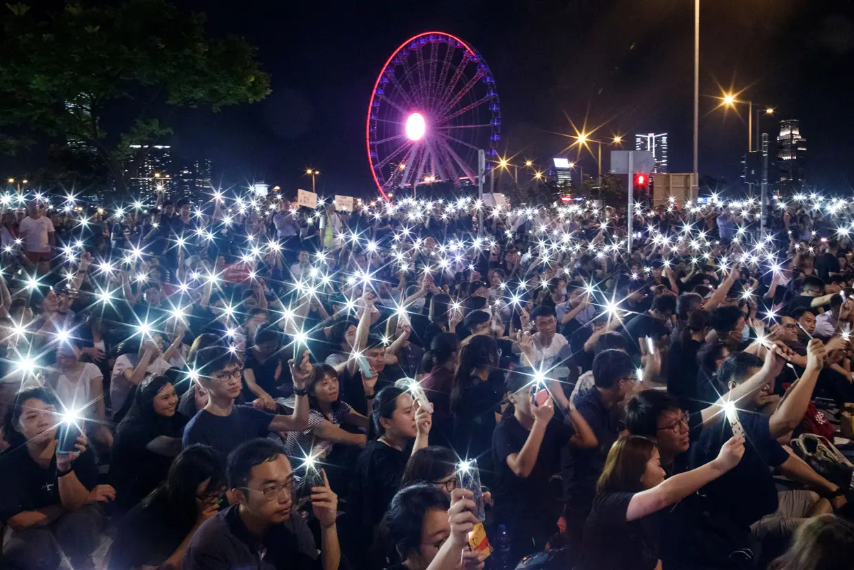 Manifestantes agitam os telemóveis durante uma ação antes da cimeira do G20, pedindo à comunidade internacional que apoie as reivindicações relativas à lei de extradição em Hong Kong, na China.