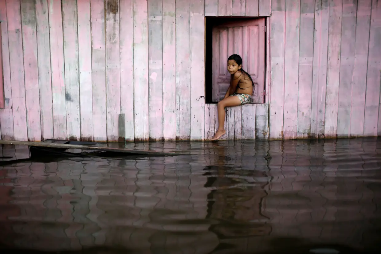 Criança numa rua inundada pela nascente Rio Solimões, no Brasil
