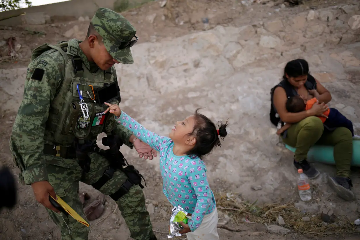 Militar da Guarda Nacional do México brinca com uma menina hondurenha que foi impedida de entrar ilegalmente nos Estados Unidos