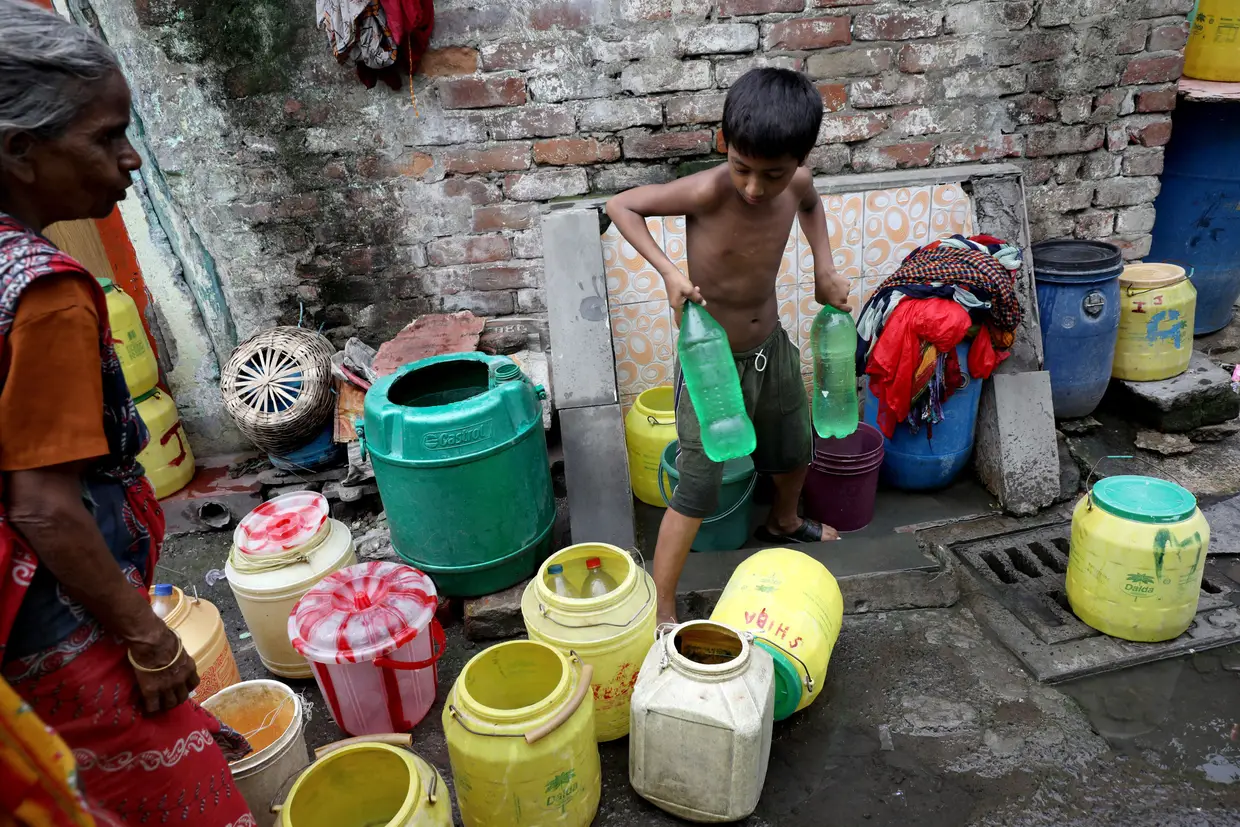 Um menino enche garrafas com água de uma fonte, num bairro de lata de Calcutá, na Índia, onde vários estados estão a ficar sem água.