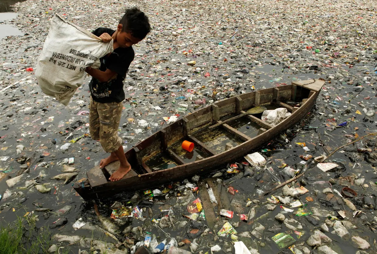 Rapaz recolhe plástico de um rio em Jacarta, Indonésia