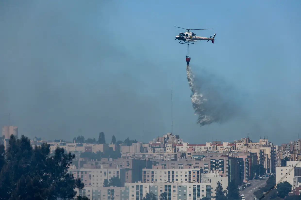 Um helicóptero efetua uma descarga de água num incêndio em zona próxima do Almada Fórum, em Vale Mourelos, na região da Charneca da Caparica que mobilizou 60 operacionais e um meio aéreo.