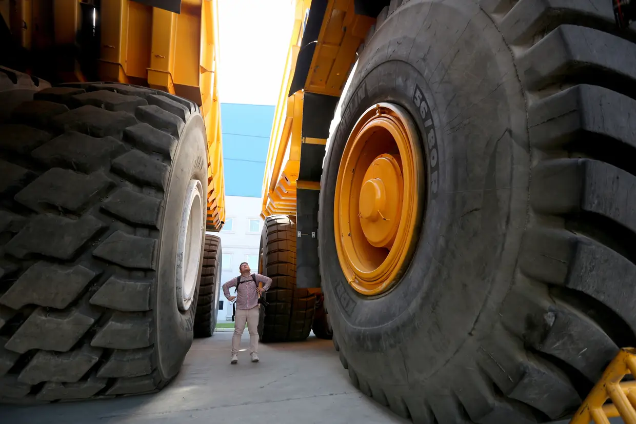 Um visitante entre dois camiões gigantes, na fábrica BelAZ, em Zhodino, Bielorrússia.