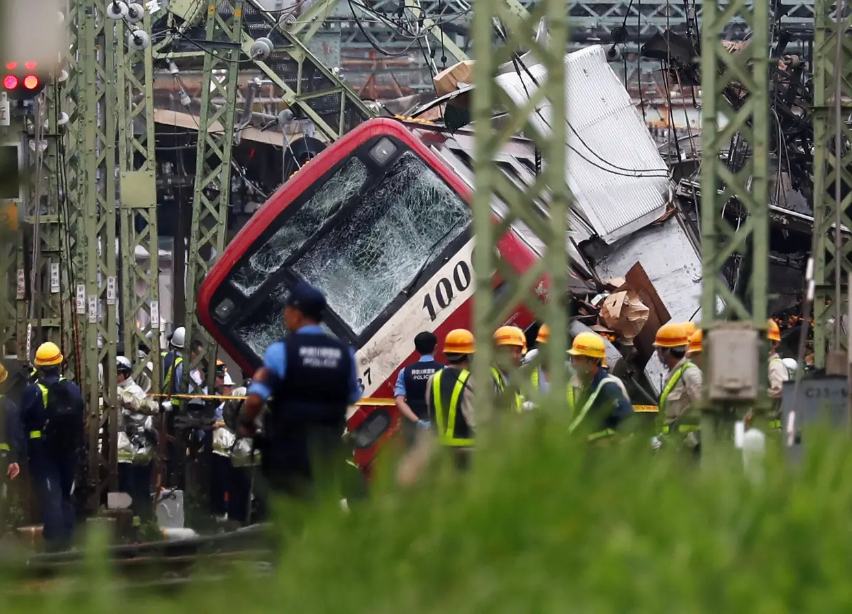 Autoridades no local do descarrilamento de um comboio após ter colidido com um camião, em Yokohama, perto de Tóquio, Japão.