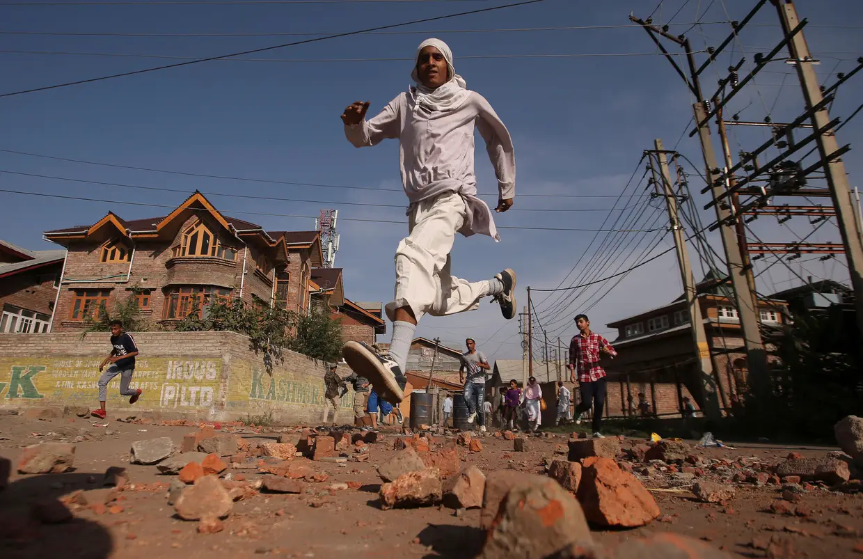 População corre enquanto as forças de segurança indianas disparam bombas de gás lacrimogénero durante protestos em Srinagar, na Índia