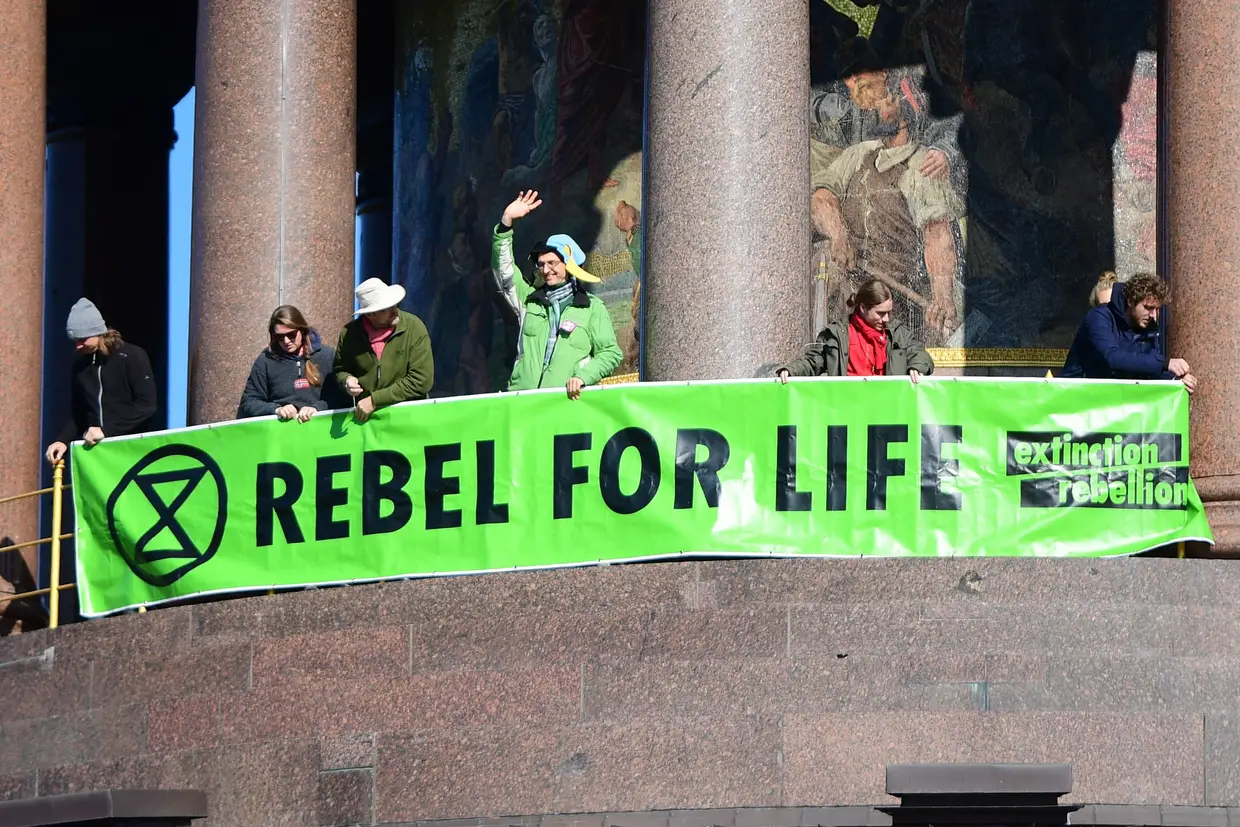 Ativistas do movimento ambientalista Extinction Rebellion desenrolam um cartaz na Coluna da Vitória em Berlim