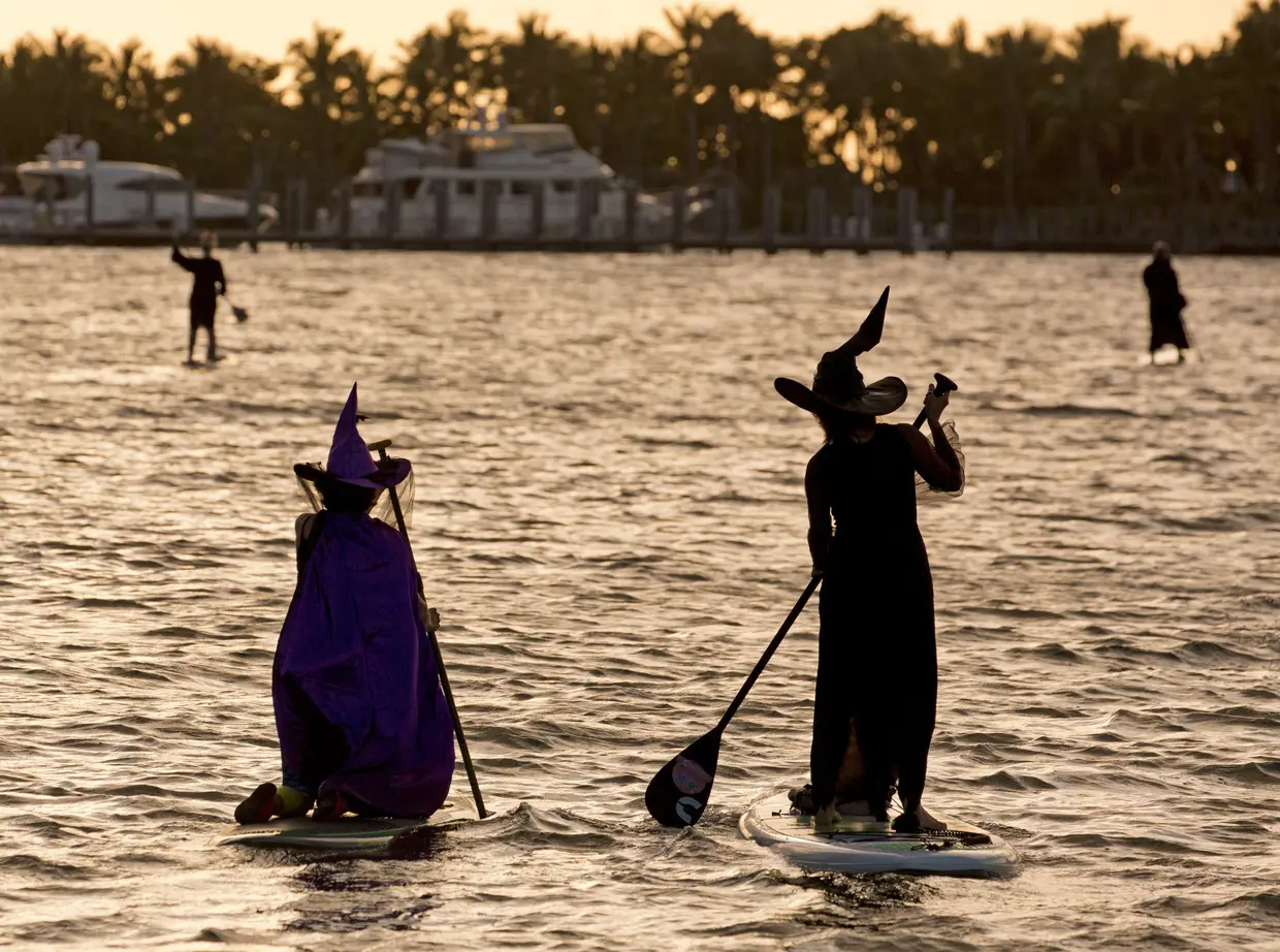 Mulheres vestidas de bruxas praticam paddle, em Florida Keys, EUA.