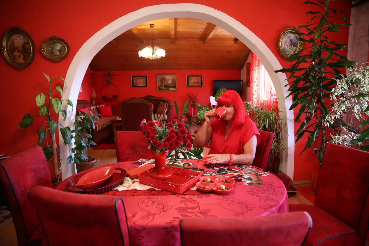 Uma mulher, obcecada com o vermelho, bebe café na sua casa, na vila de Breze, Bósnia-Herzegovina.