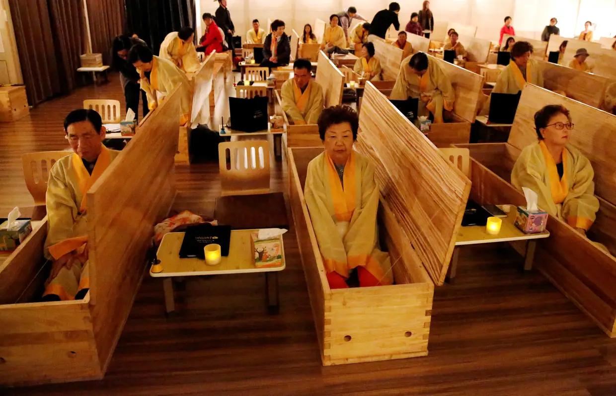 Participantes sentam-se dentro de caixões durante um "funeral vivo" que faz parte de um programa sobre "como morrer bem", em Seul, na Coreia do Sul