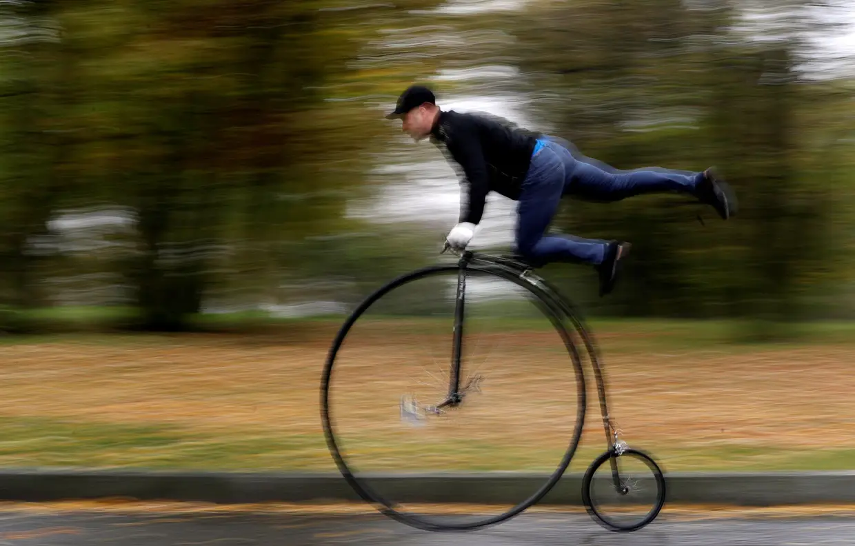 Um participante de trajes históricos equilibra-se na sua bicicleta de roda alta durante corrida anual em Praga, na República Checa
