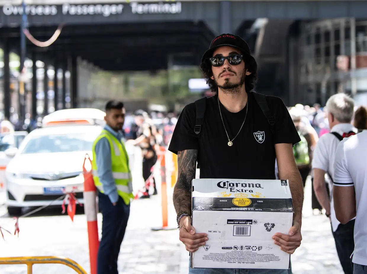 Um homem carrega uma grade de cerveja Corona junto ao terminal de passageiros em Sydney onde atracou o cruzeiro norueguês onde existem suspeitas de infeção por coronavírus.