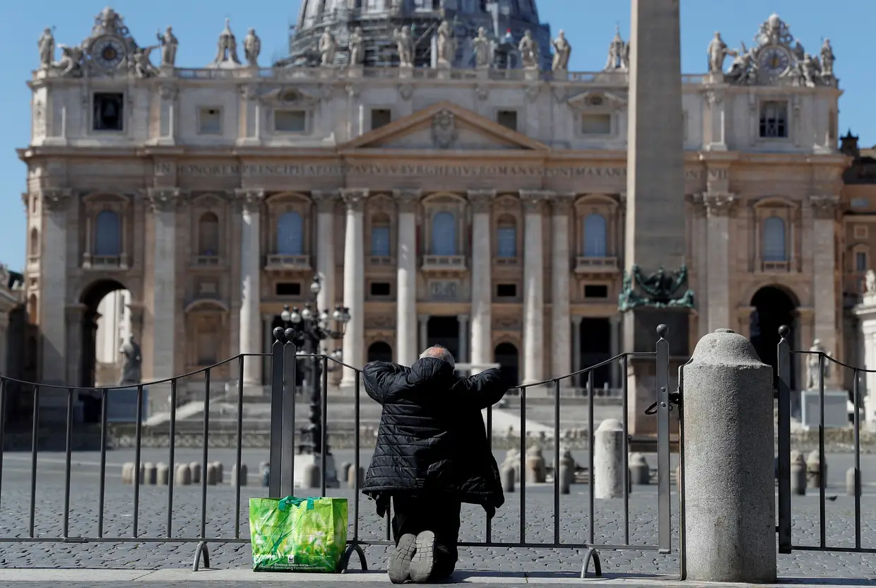 Um homem reza em frente à Praça de São Pedro, no Vaticano, Roma, Itália.