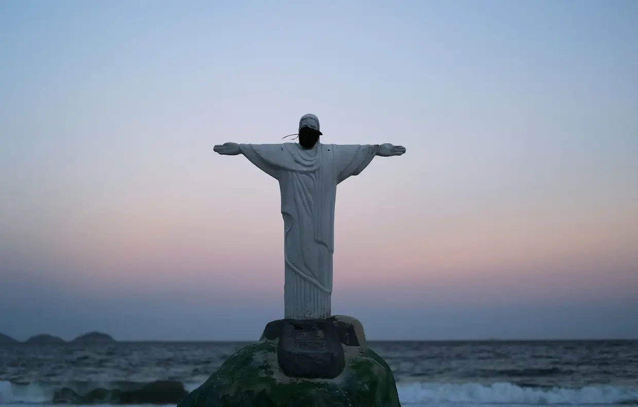 Uma escultura em areia do Cristo Redentor a utilizar uma máscara de proteção, na praia de Copacabana, no Rio de Janeiro, Brasil.