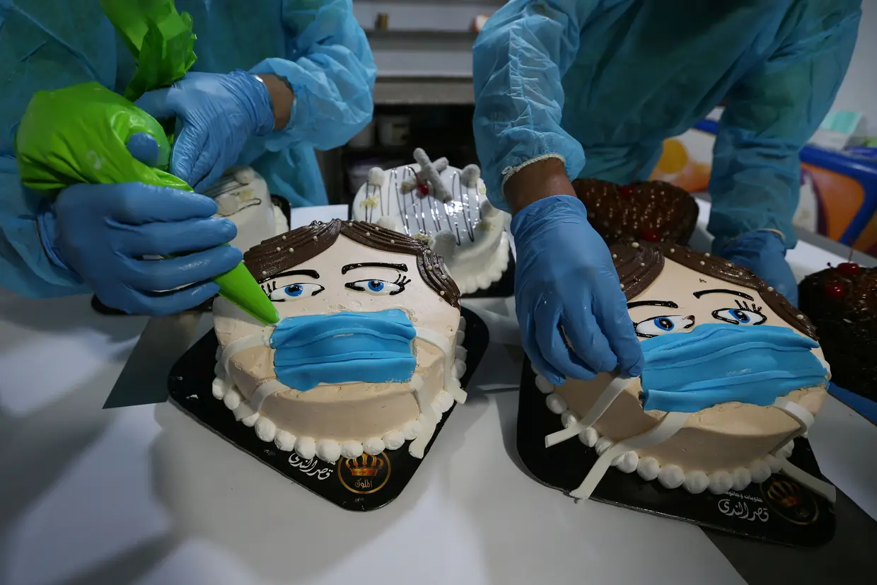 Palestinianos decoram bolos em forma de uma pessoa a utilizar uma máscara de proteção numa pastelaria em Khan Younis, na Faixa de Gaza.