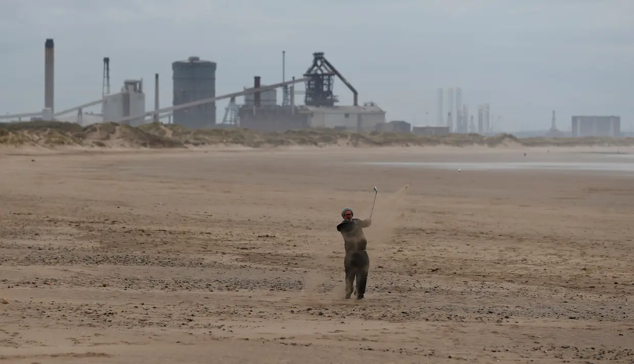 Um homem joga golfe numa praia em Redcar, Inglaterra.