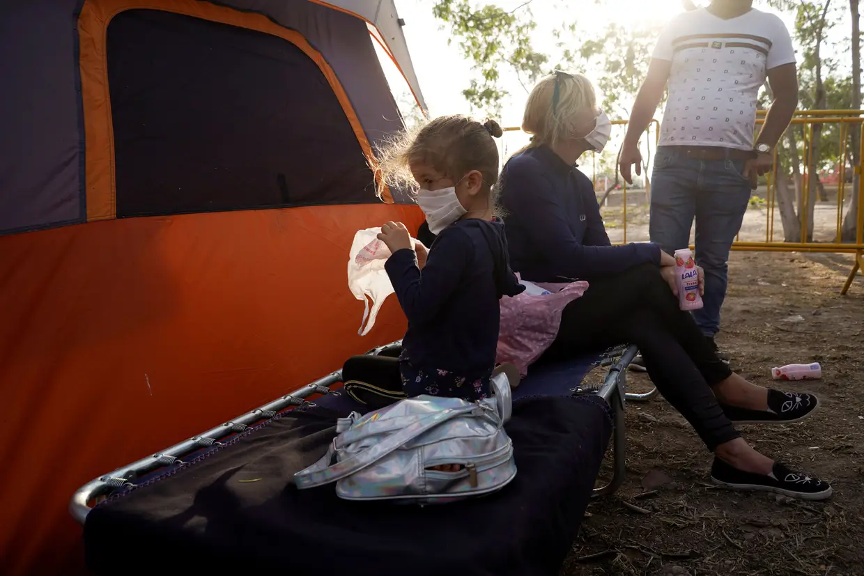 Yanisleydi de la Rosa, de 34 anos, e a filha, de quatro anos, utilizam máscaras de proteção num campo de migrantes no México, enquanto aguardam por asilo nos Estados Unidos.
