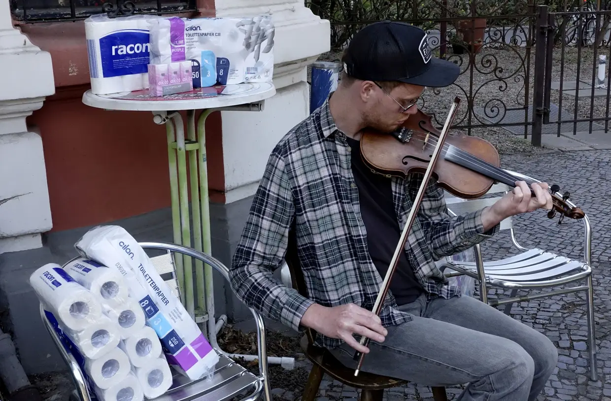 Jovem toca violino durante uma campanha de doação de papel higiénico em Berlim, Alemanha