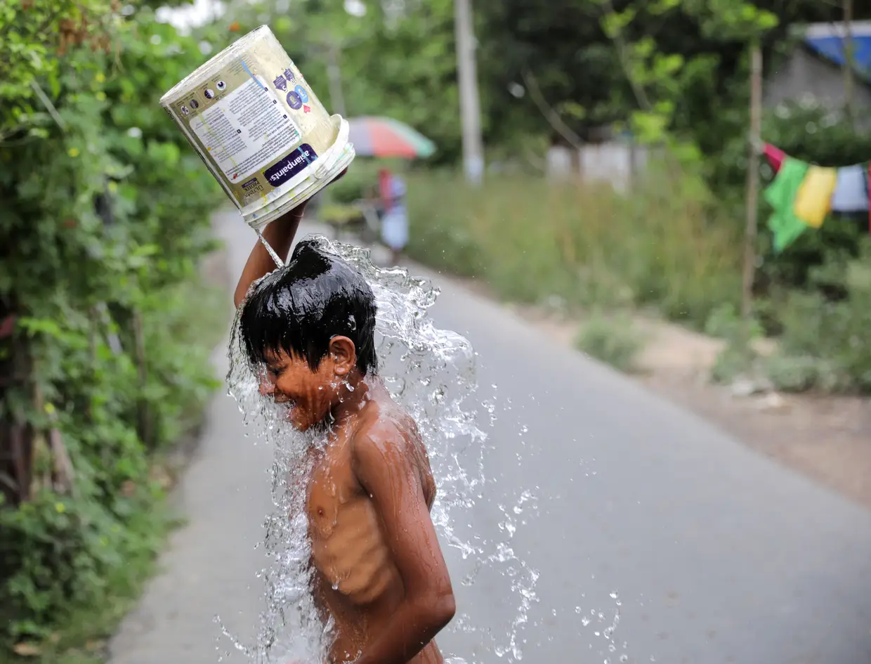 Uma criança toma banho na rua durante o confinamento decretado em Calcutá, na Índia, devido à pandemia do novo coronavírus.