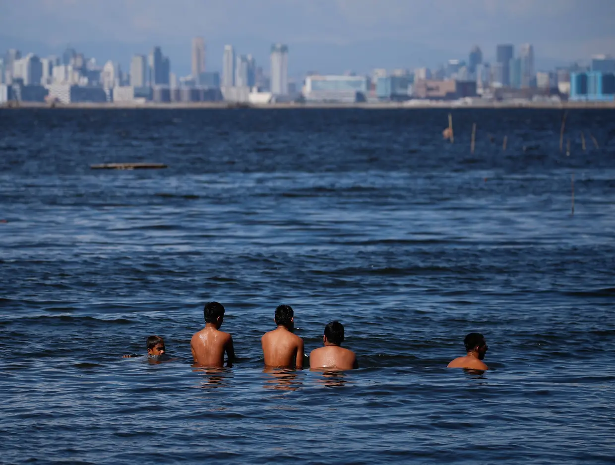 Locais nadam na lagoa de Manila, Filipinas.