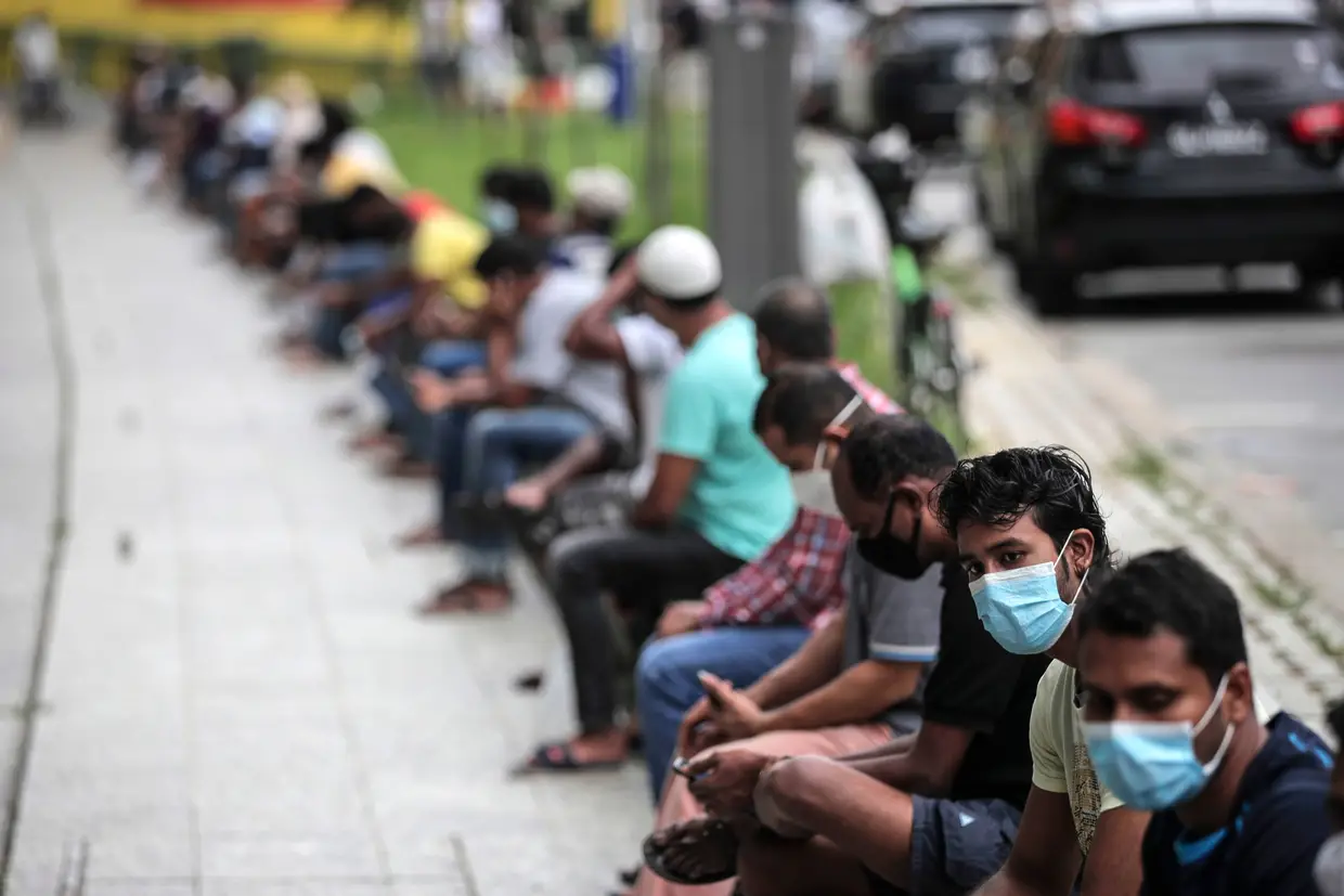 Trabalhadores migrantes numa fila para receber refeições, Singapura.