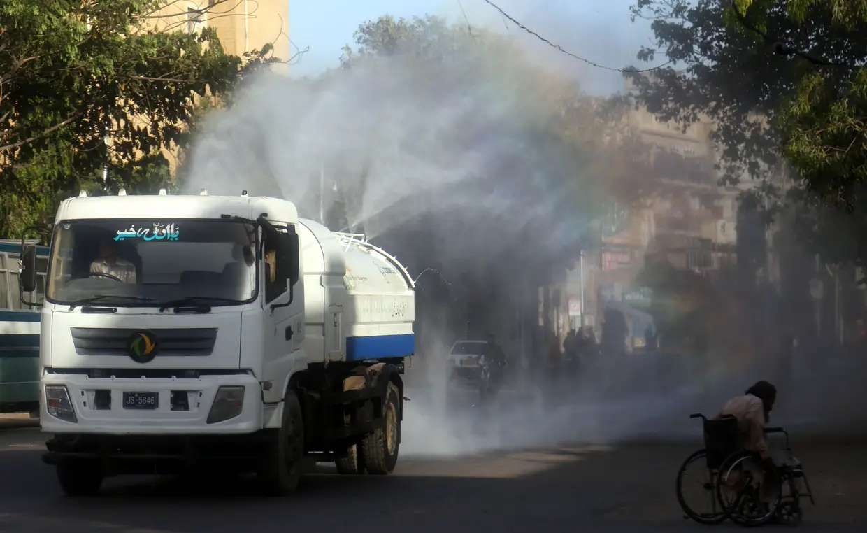 Trabalhadores desinfetam uma rua de Sindh, em Carachi, Paquistão.