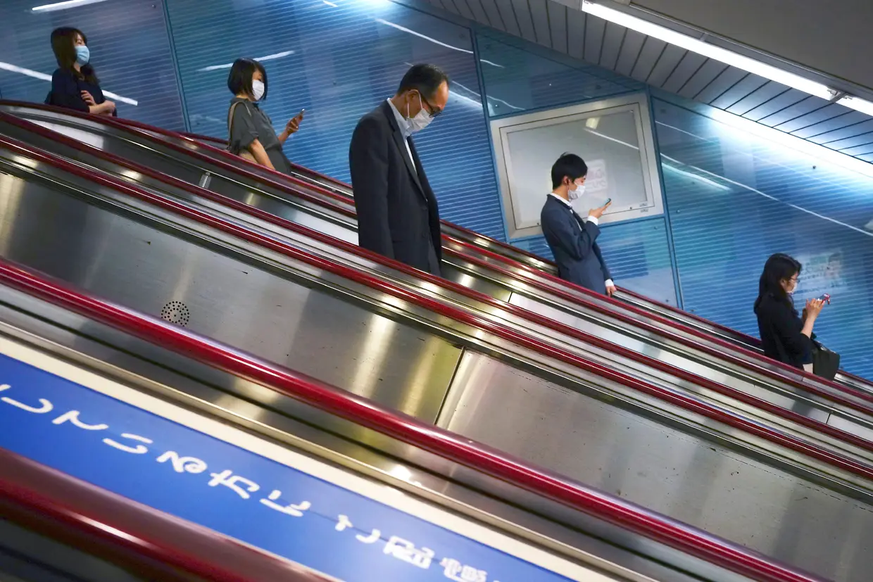 Pessoas a usar máscara numa estação de metro em Tóquio, Japão.